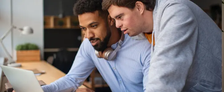 an adult and a special needs child looking at a laptop